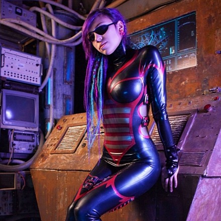 Purple Haired Girl In A Red And Black Latex Catsuit With Kneehigh Boots
