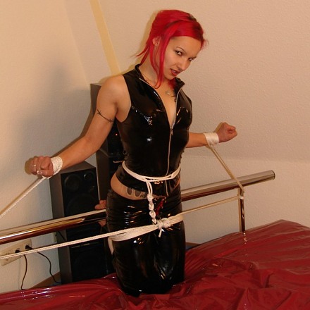 Hot Redhead Fetish Girl In Black Pvc Outfit Gagged And Roped On Bed