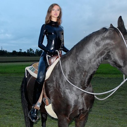 Beautiful Princess Fatale In A Shiny Black Latex Catsuit And Riding Boots On Horse
