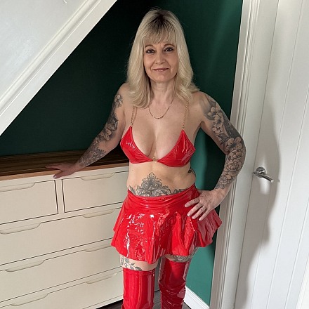 Inked Milf Teases At Home In A Red Pvc Bra With Matching Miniskirt And Thighhigh Boots